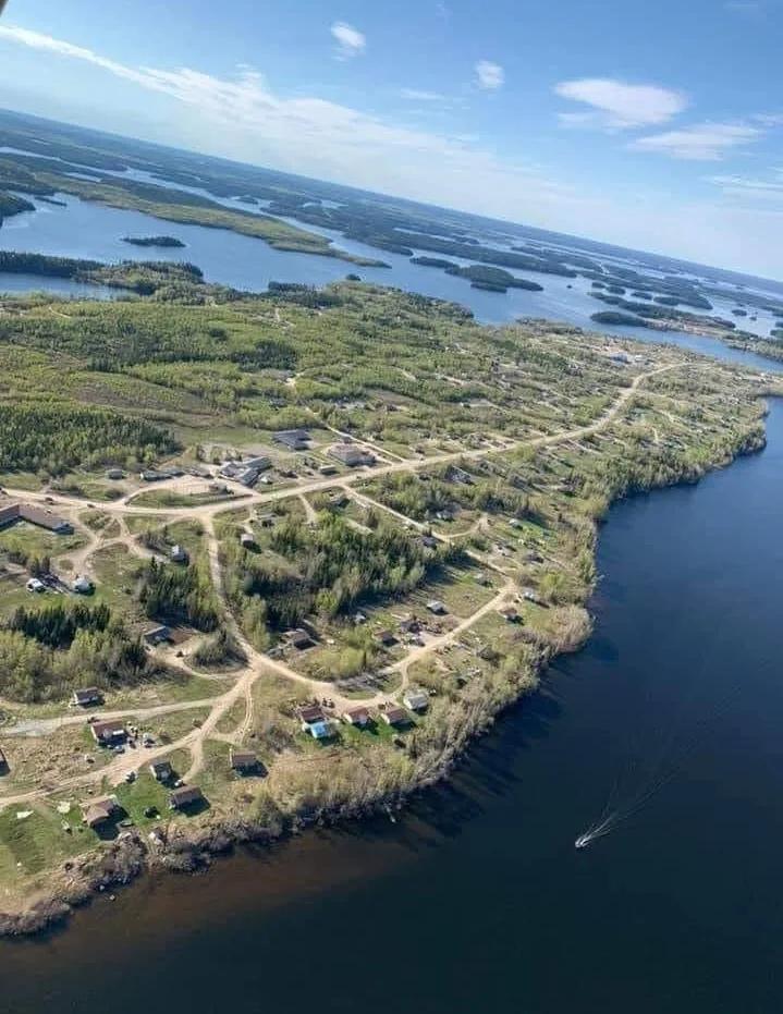 Aerial photograph of a lakeside community with homes, roads, forested areas, and interconnected waterways extending across the landscape.