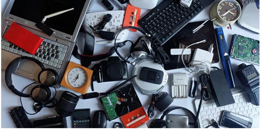 Overhead view of various electronic devices  arranged on a cluttered surface.