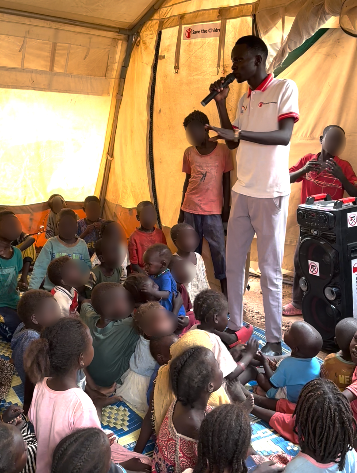 CH11013472_Stephen Kang singing with children in Save the Children's Child Friendly Space in Transit
