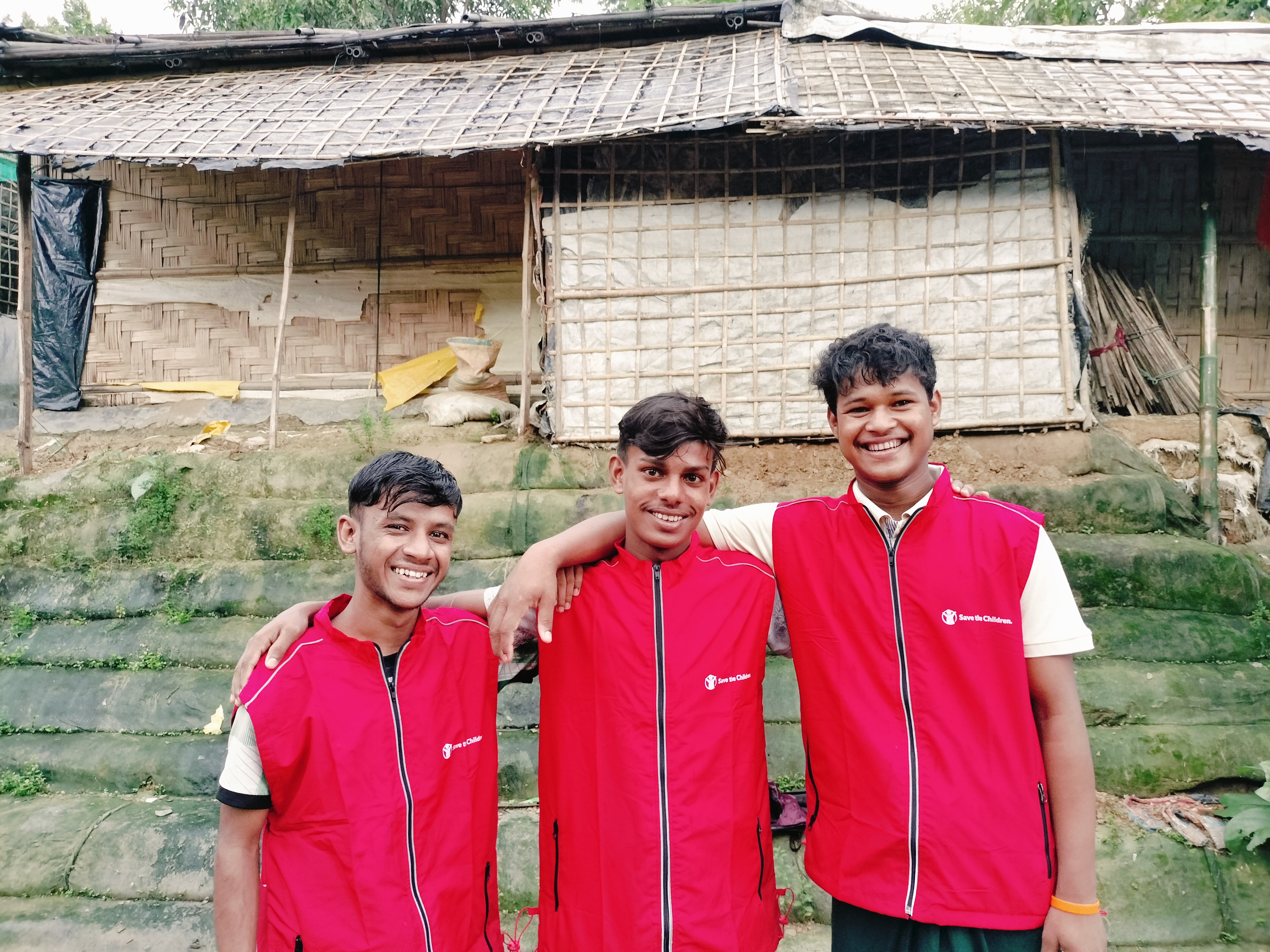 Musa (left), Nobi (middle) and Hakim (right) pose a photo near a wall they helped to repair.