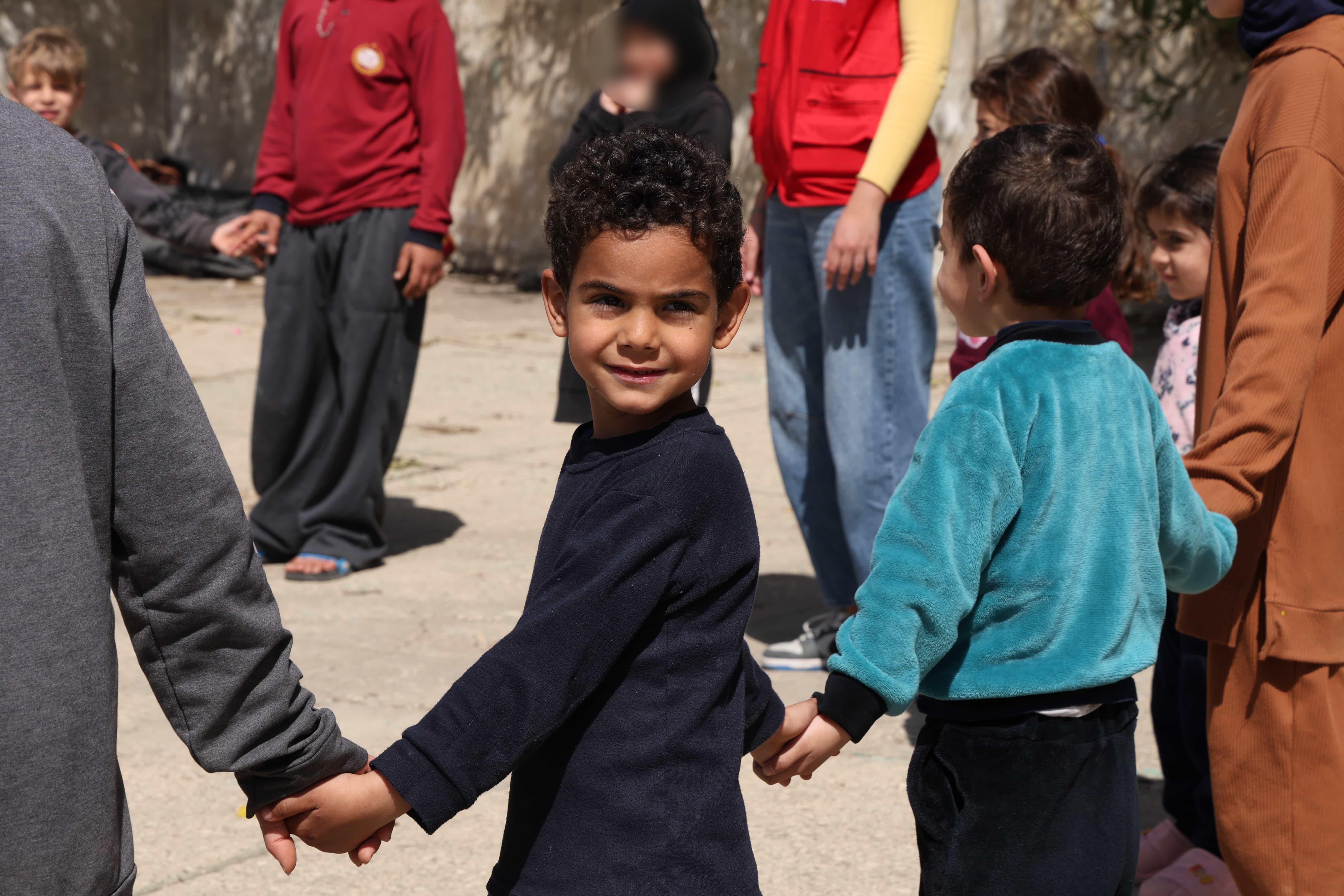 CH11557061_5 year old Imad holds hands with other children at a Child Friendly Space