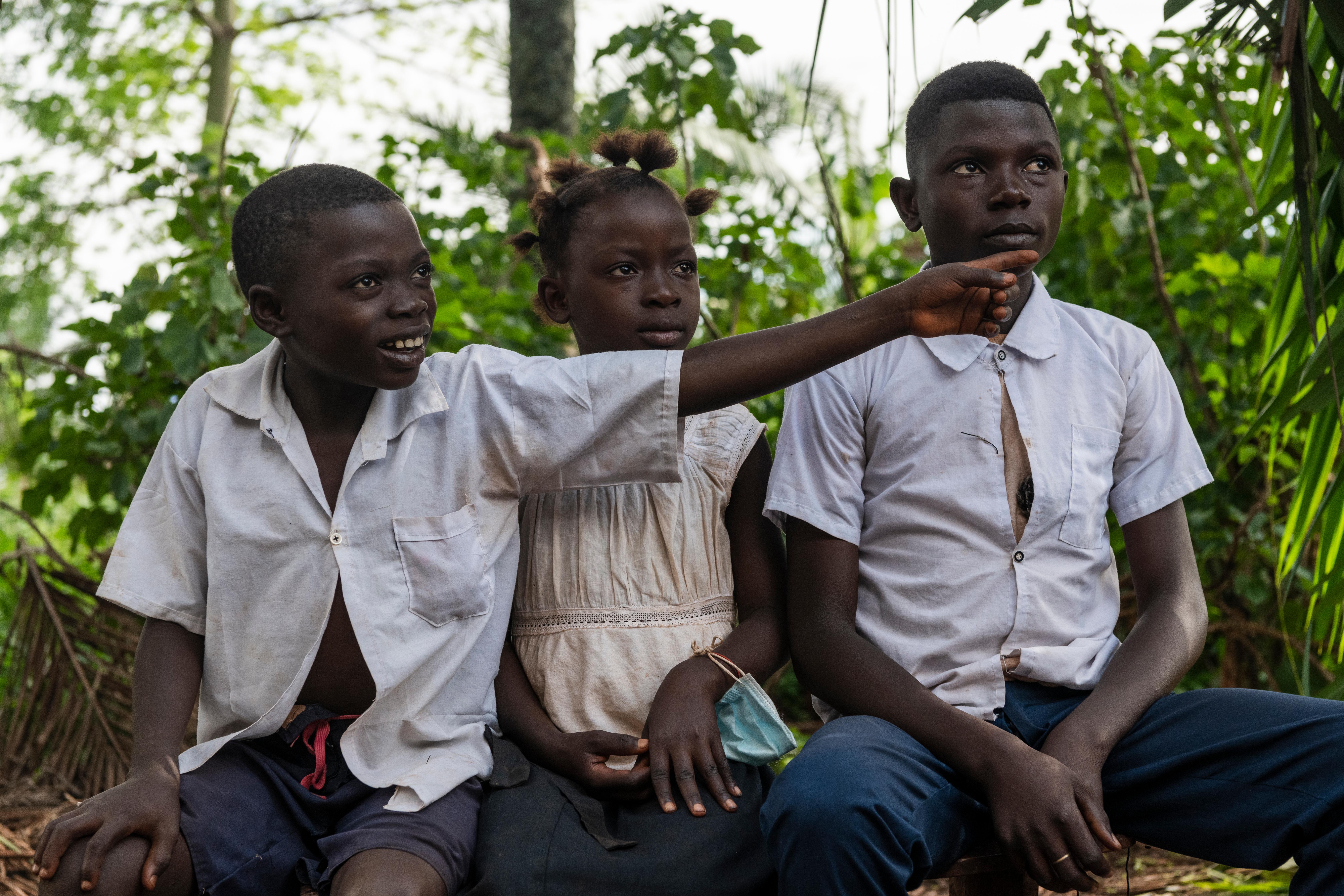 Mushiba, aged 9, with her brothers Samuel (left) and Nambwa (right) outside their home in Lomami Province DRC.