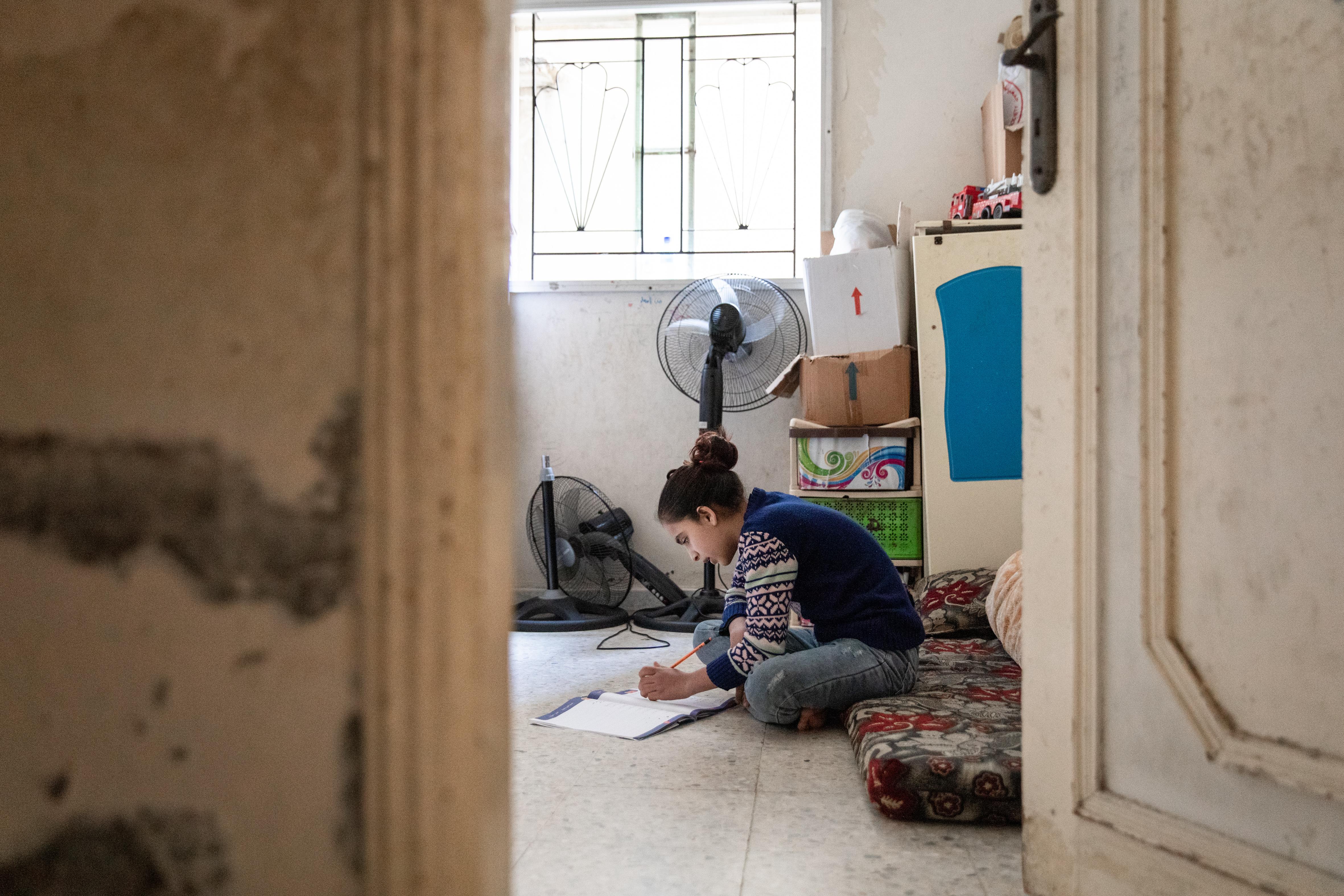 CH1689597_Ghinwa, 13, doing her home work at her home in a refugee settlement, in Beirut, Lebanon