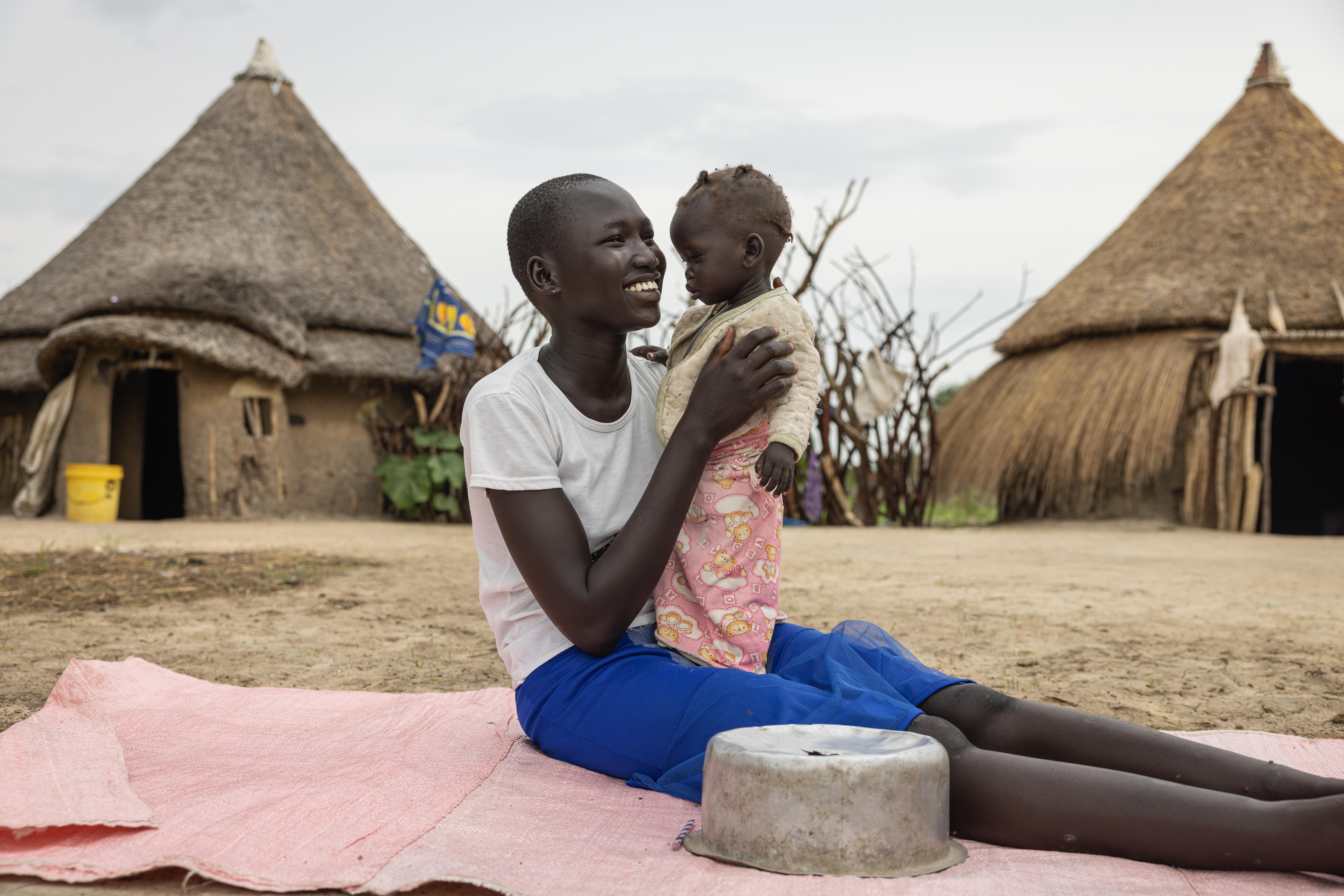Ayen plays with Nyajuba outside their home.