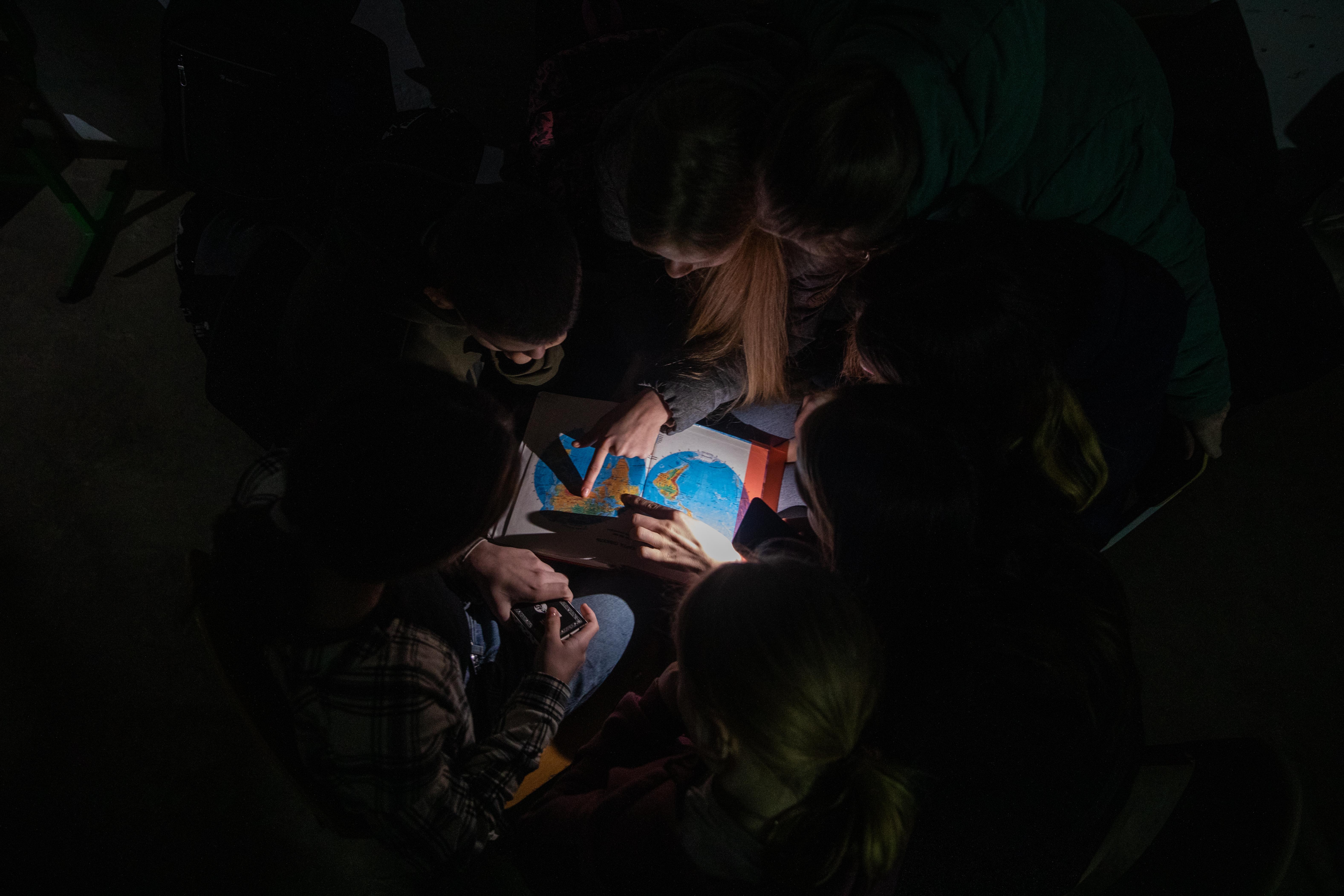 CH1765662_Students gather around the map while they take shelter in a school basement in Chernihiv r