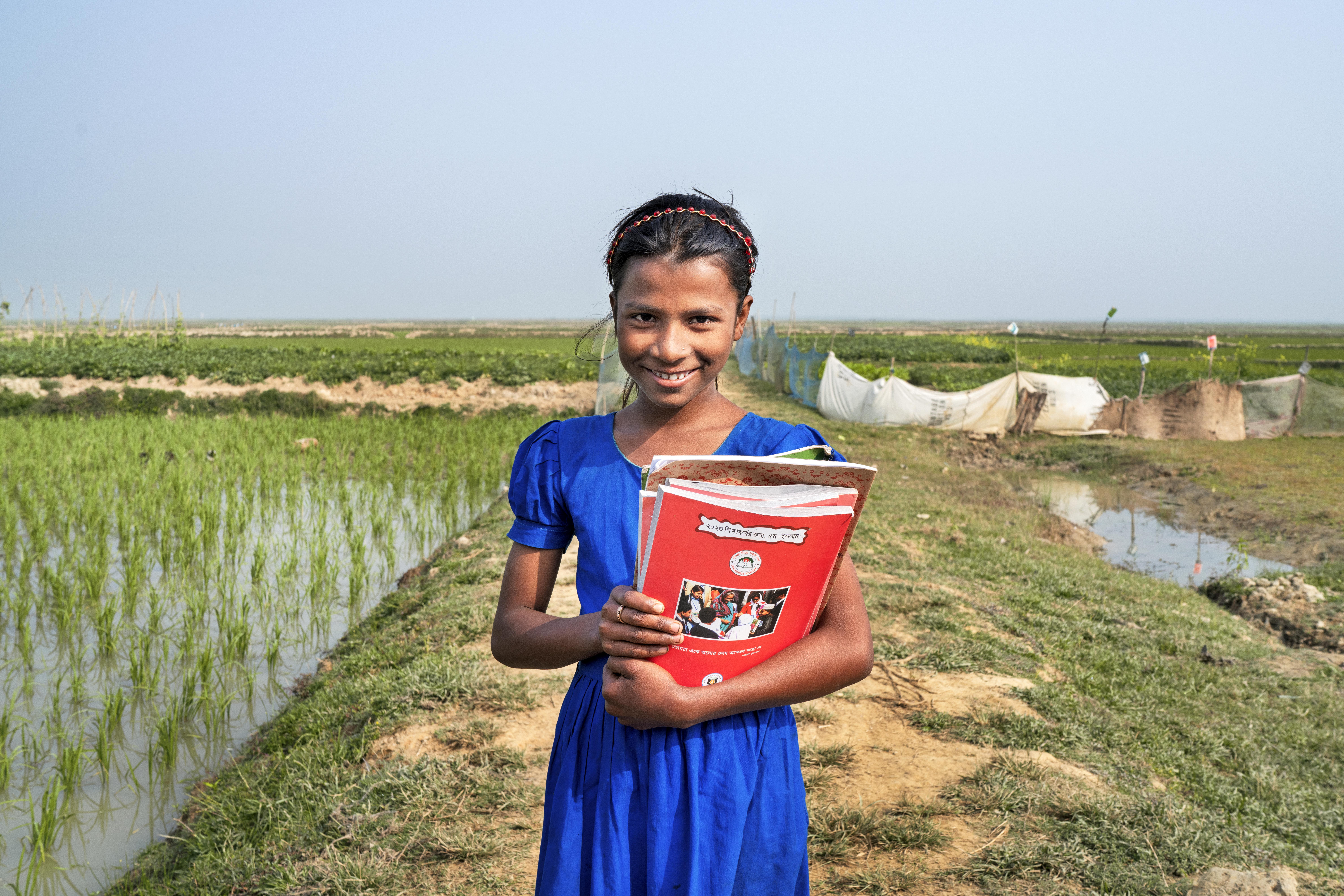 CH1771759_Portrait of Tanni, 12, with her school books outside her home in Sylhet, Bangladesh
