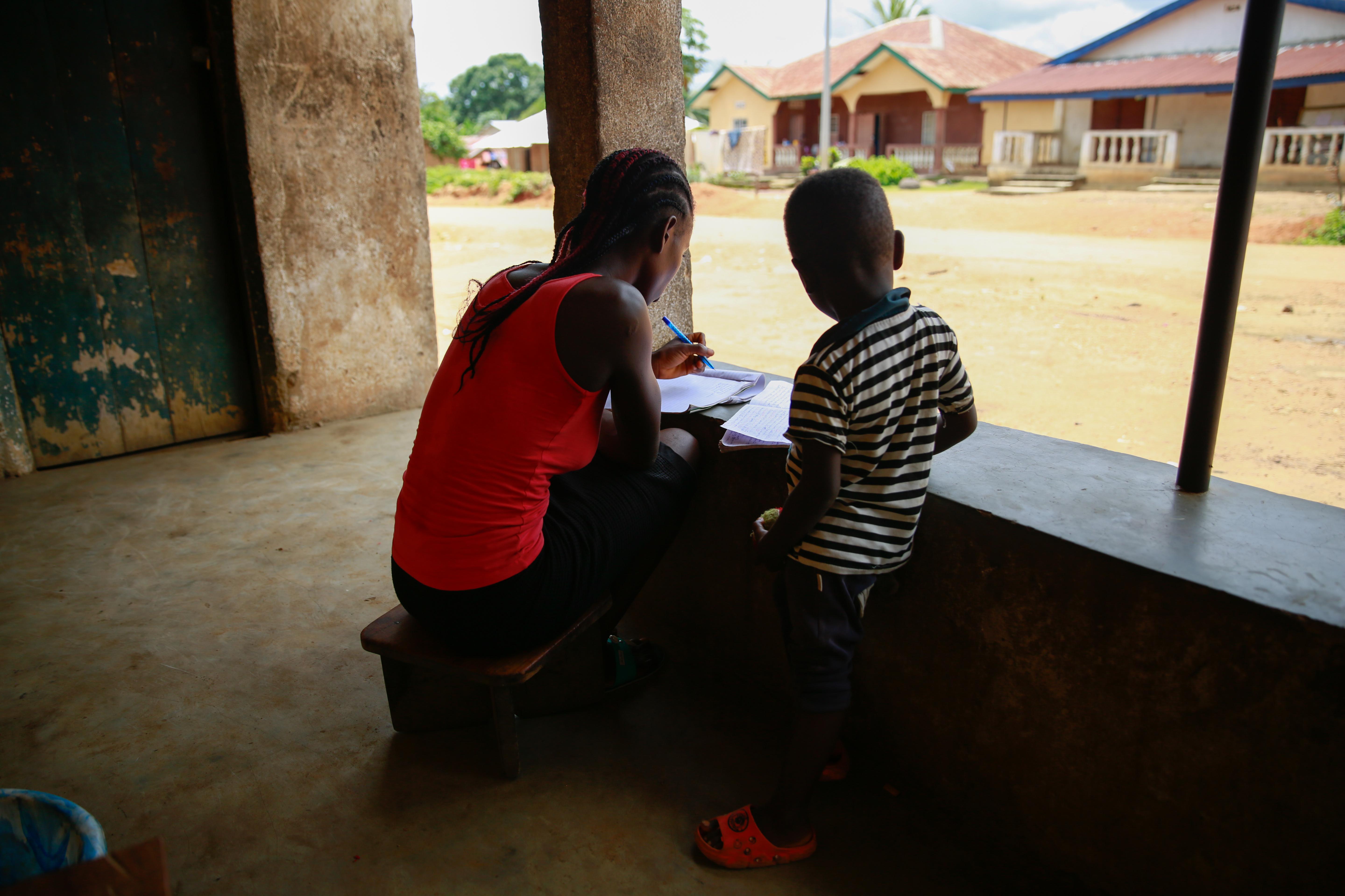 CH1872377_Kuji-19-studies-at-home-with-her-3-year-old-son-in-Kailahun-Sierra-Leone