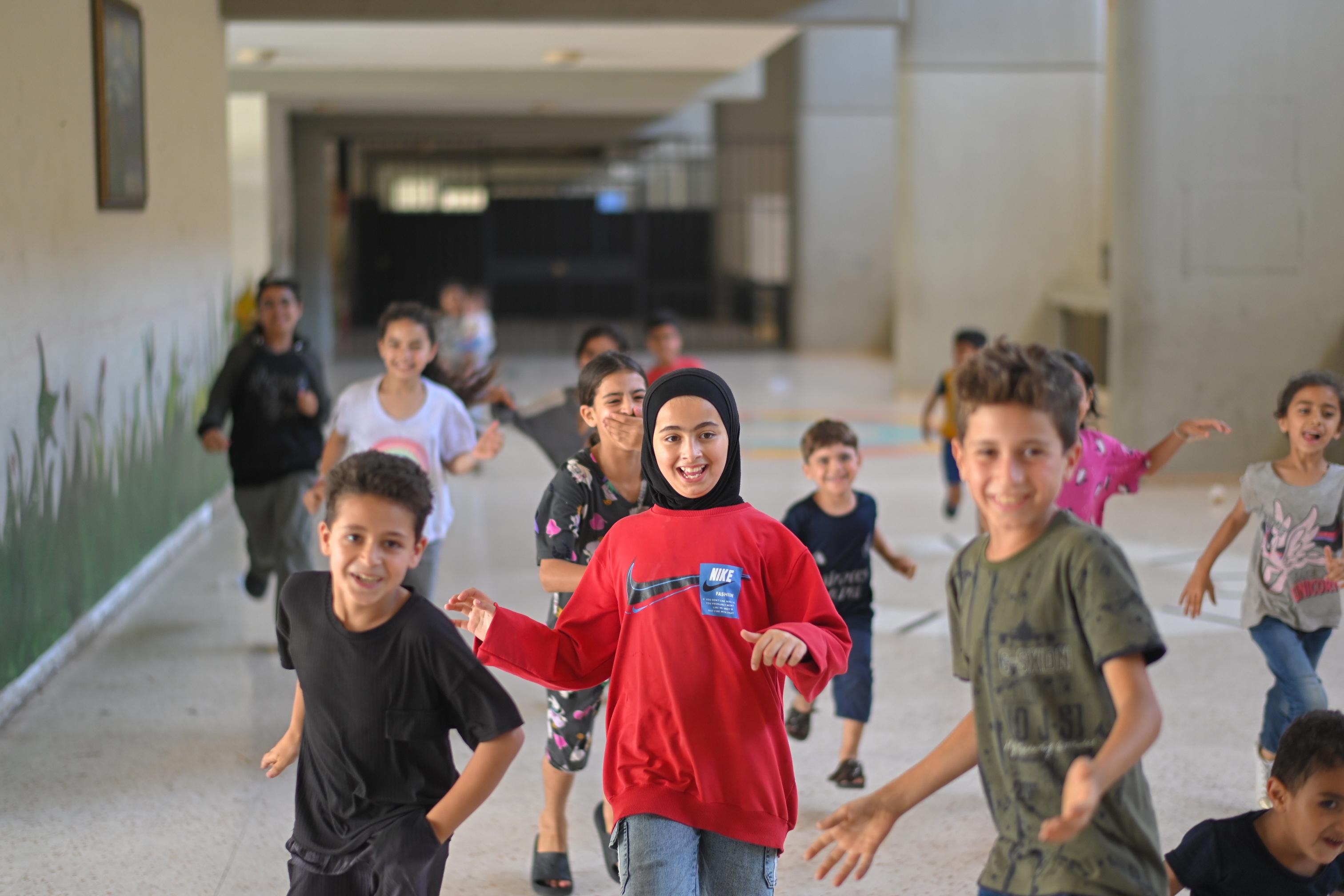 Children smile and run at a collective shelter