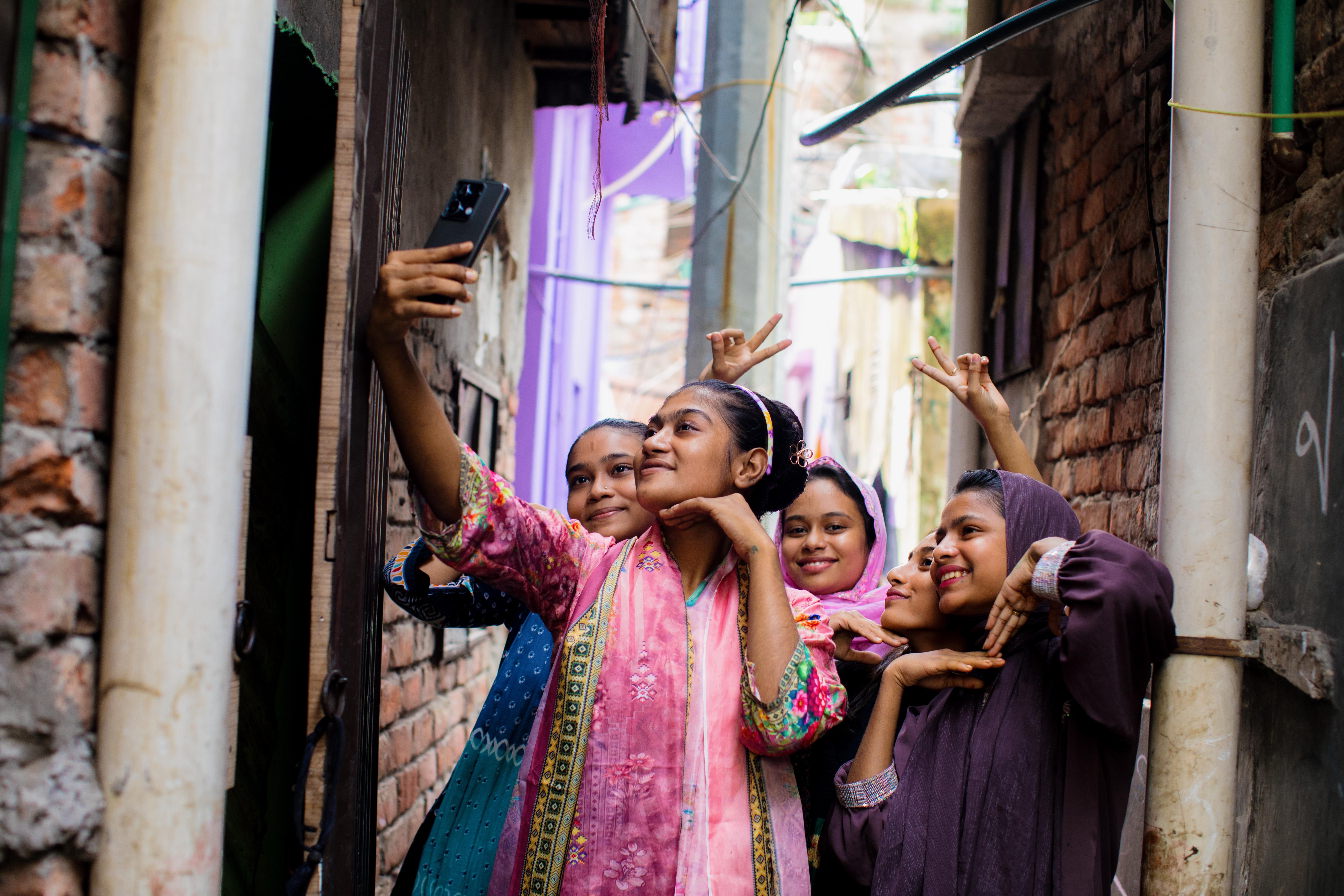 Girls gather round in a narrow street in Dhaka, Bangldesh, to take a selfie.