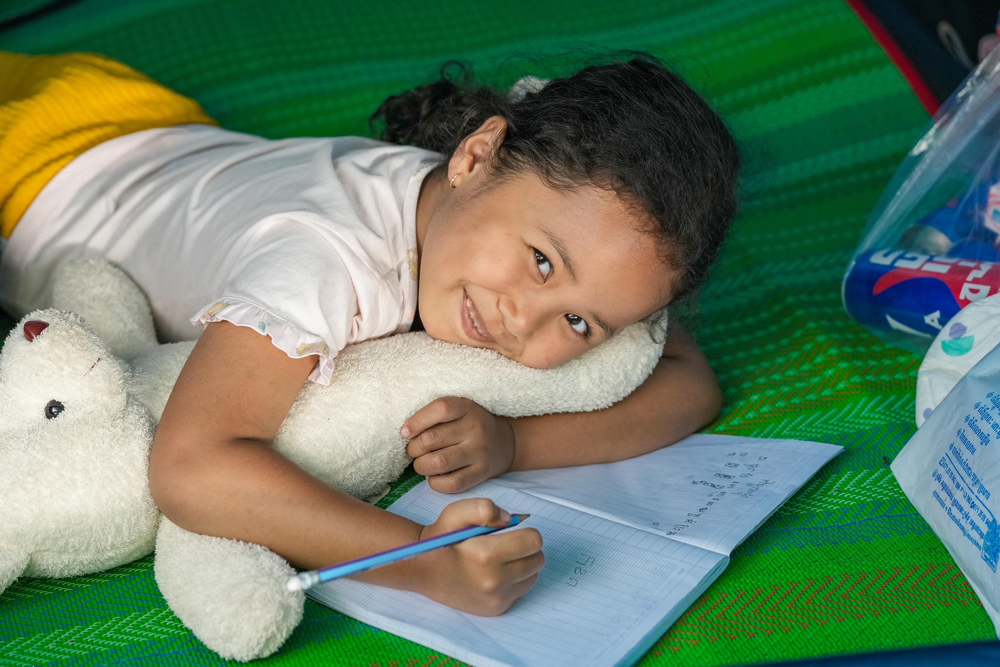 Kanika*, 5, happily drawing in camp