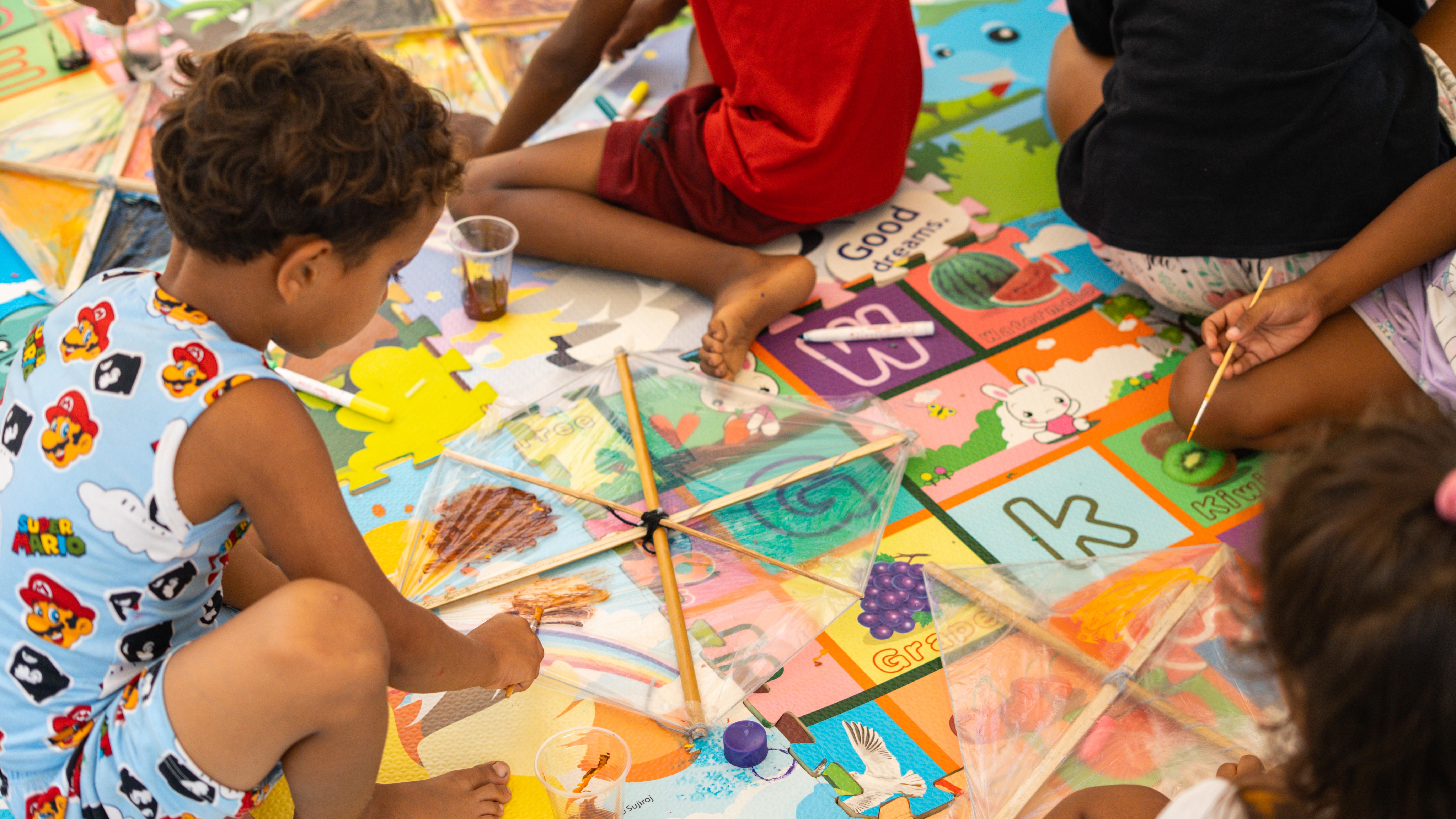 Ramón*, 5, and friends decorating their kites with stickers before flying them