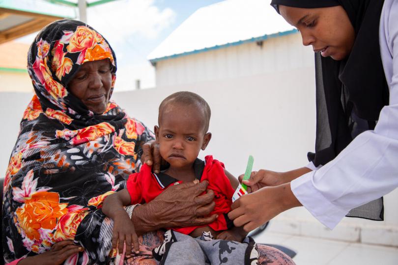  A Save the Children nurse checks Abdi's* arm with a MUAC tape to determine his malnutrition level.