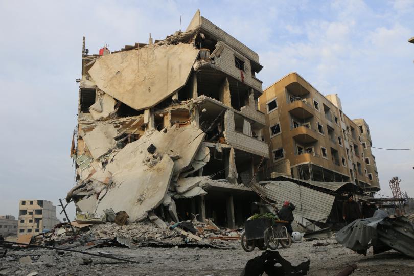 A child walks past a bombed building