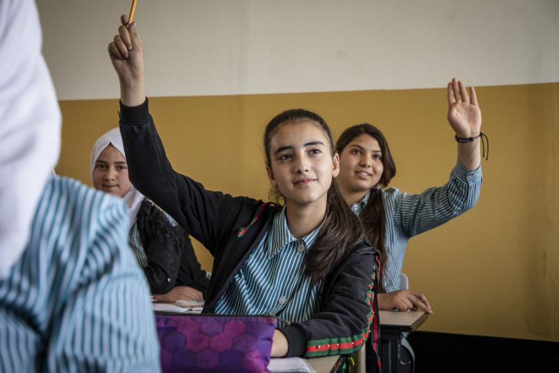Rima*, 13, raises her hand in class at her school in the occupied Palestinian territory (oPt)