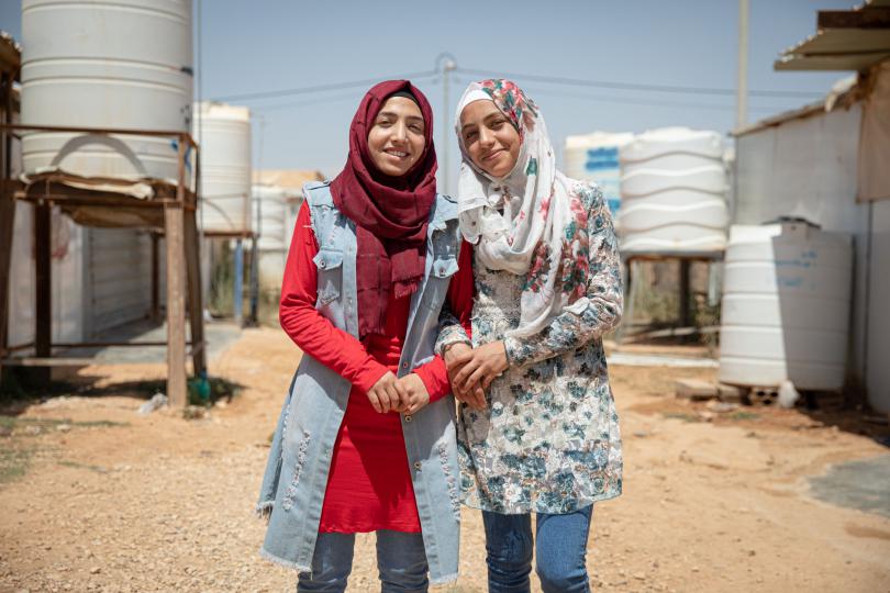 Hiba* (red shirt), 17, and Rama*, 14, pose for a portrait outside their family caravan in Za’atari camp for Syrian refugees, Jordan.