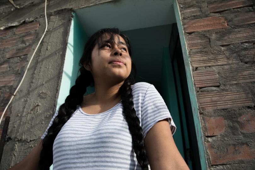 Estefany*, 15, stands in a courtyard in her home in Huanuco, Peru