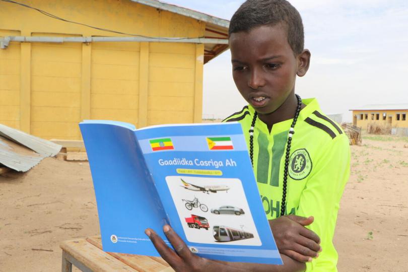 Nassir, 12, reads a book from Save the Children's mobile reading camp, when he is out of school because of the coronavirus, Ethiopia.