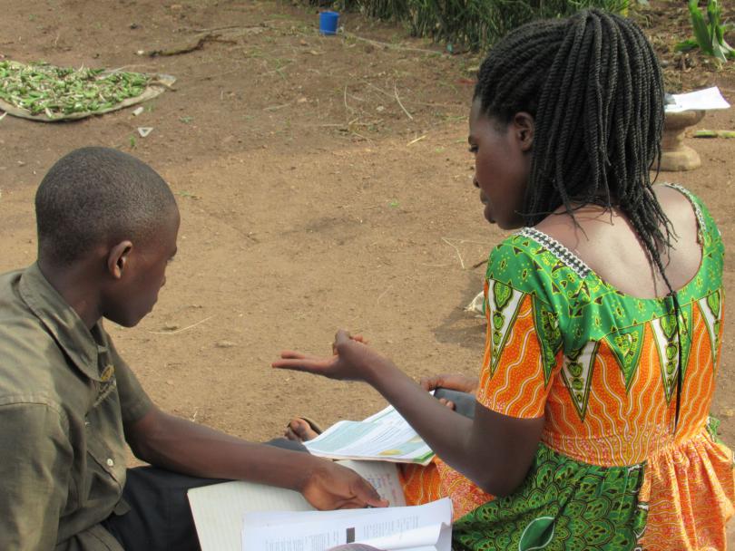 A teacher sits with a child in Uganda