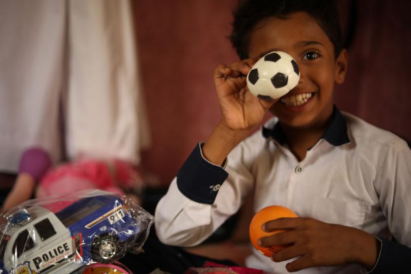 Aiman*, 12, plays with toys in his home in Yemen. Aiman* has brain atrophy which makes it difficult for him to move, walk or write. He loves school but is frustrated that he relies on the teachers to write the answers for him. Since COVID-19, Aiman's school has been closed.