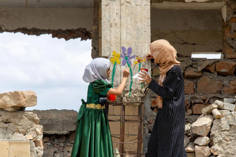 Children in Yemen paint a flower mural on the walls of a destroyed school as part of the Flowers for Children campaign