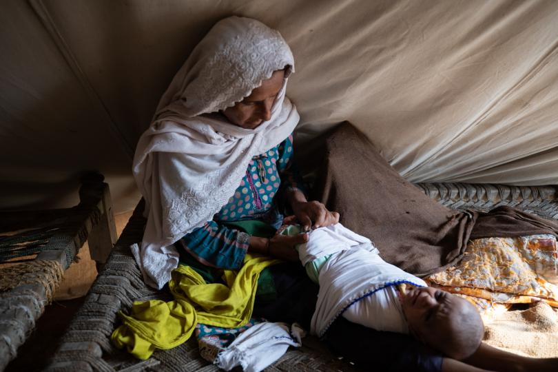 Noor with her newborn baby, inside her waterproof tent provided by Save The Children, Sindh, Pakistan