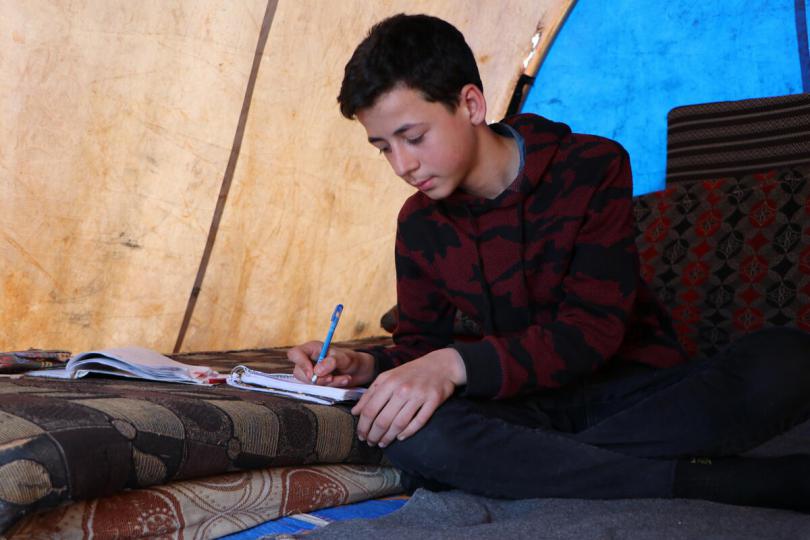  Hatem*, 15, studying in the tent where he now lives after he lost his house to the earthquake.