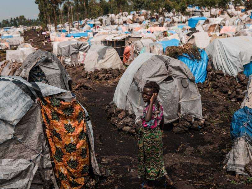 A young girl walks through rows of tents in a displacement camp in the Democratic Republic of Congo