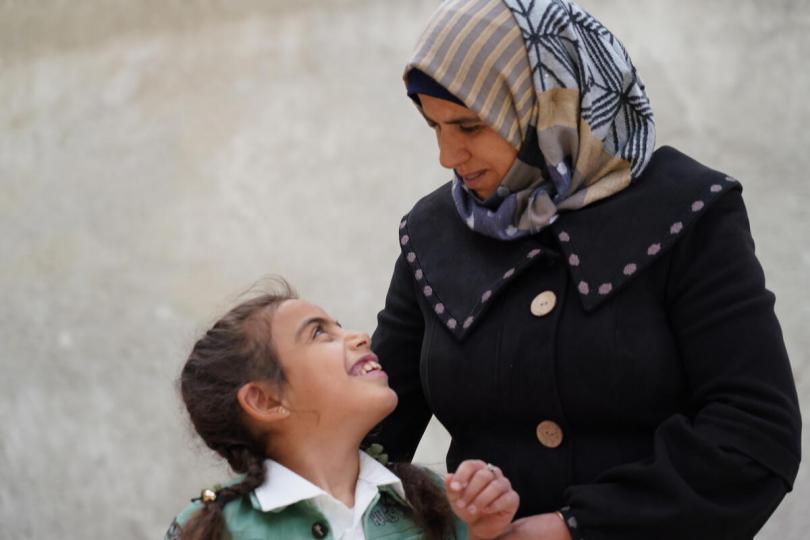 Widad*, 8, looks up at Ghalia*, 41, during a psychosocial support session
