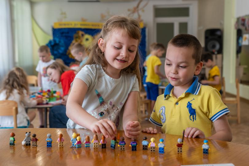 Boy and girl play with figures of citizens of dream city created with Lego constructor by children
