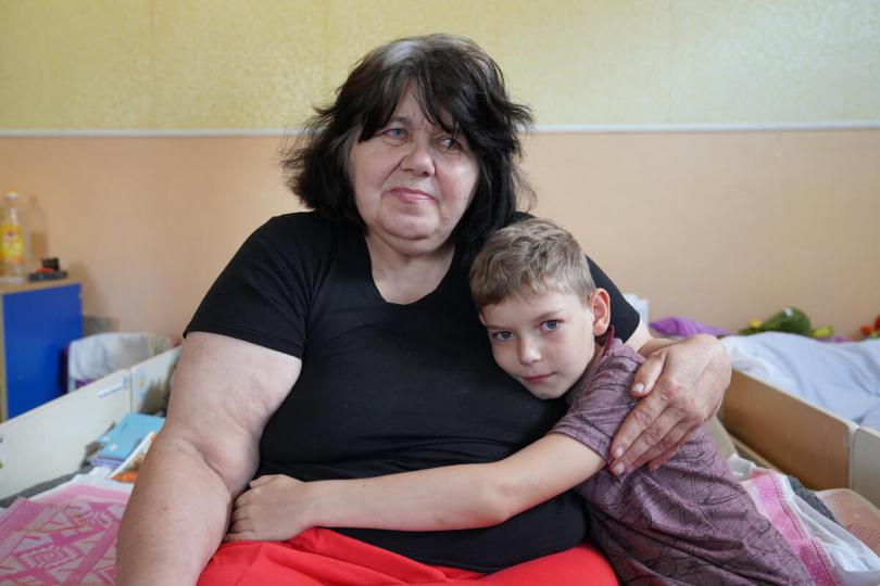 Mykola*, 9 and his grandmother Daryna*, pose for a photo in a kindergarten which is their home now in Poltava, East Ukraine
