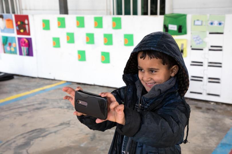 Yazan*, 7 years old, takes photos on a staff member's phone after a day in Zaatari Camp's Kindergarden
