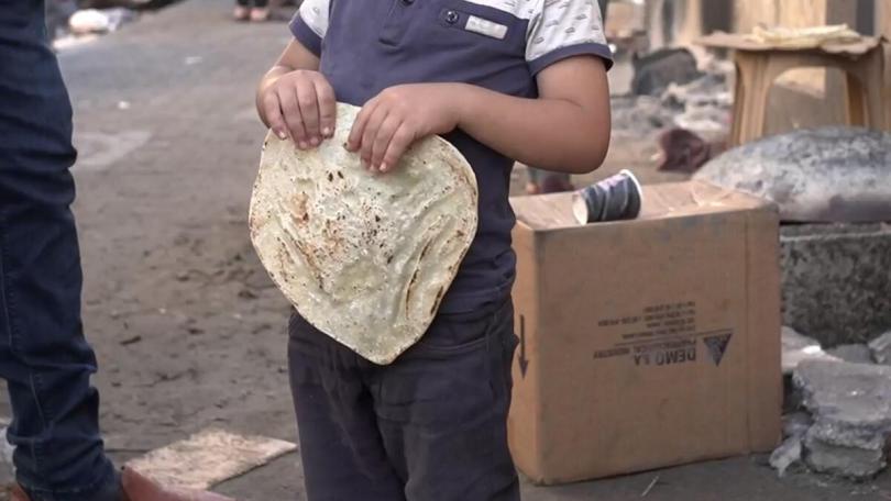 A young boy holds some bread on a street in North Gaza