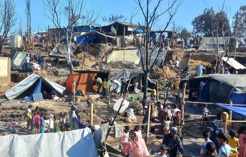 People walk through damaged tents and makeshift accommodation in the aftermath of a fire at Cox's Bazar