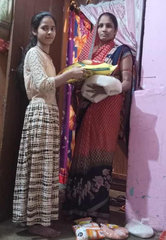 Nisha and her mother hold food supplies.