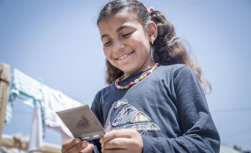  Nirmeen*, 10, examines the Polaroid photo taken by her brother, Siraj*, in an informal tented settlement in the Bekaa Valley, Lebanon. 
