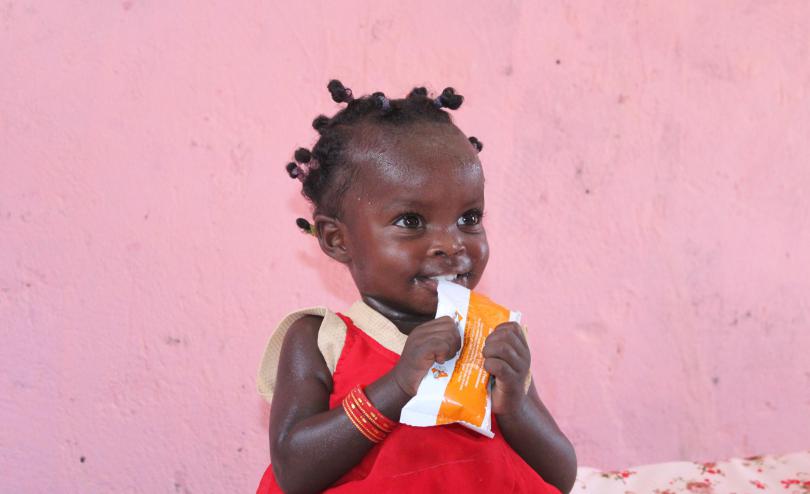 Adan*, 18 months, holds a sachet of RUSF nutrition supplement provided to children suffering from Moderate Acute Malnutrition.