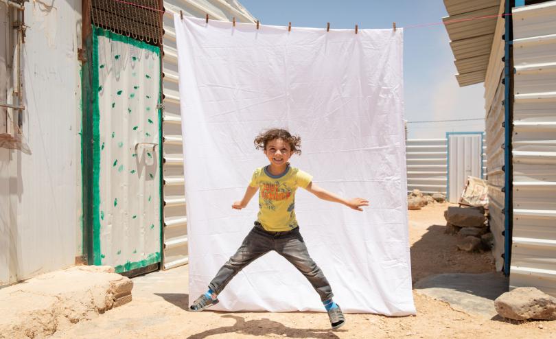 Faisal*, 5, poses for a portrait outside his family caravan in Za’atari camp for Syrian refugees, Jordan.