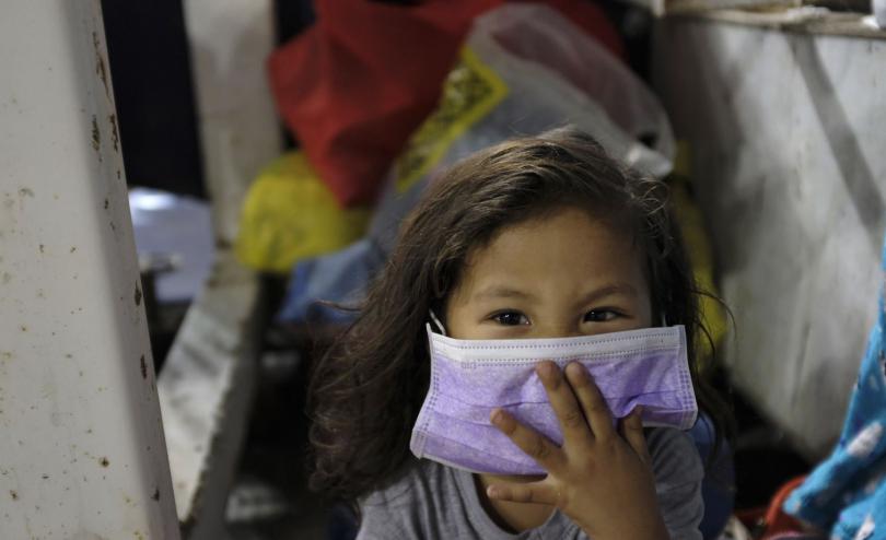 A girl holds a mask to her face