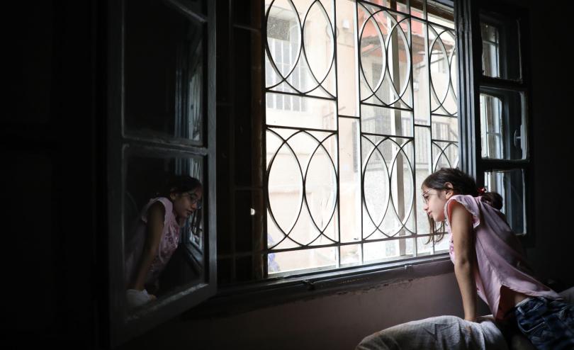 Lama*, 11, looks out the window of their house which was damaged during the Beirut explosion, Lebanon