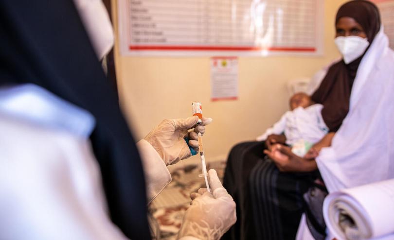 A Save the Children nurse prepares to vaccinate Abdirahman (3 months) while his mother Lucky (29) holds him