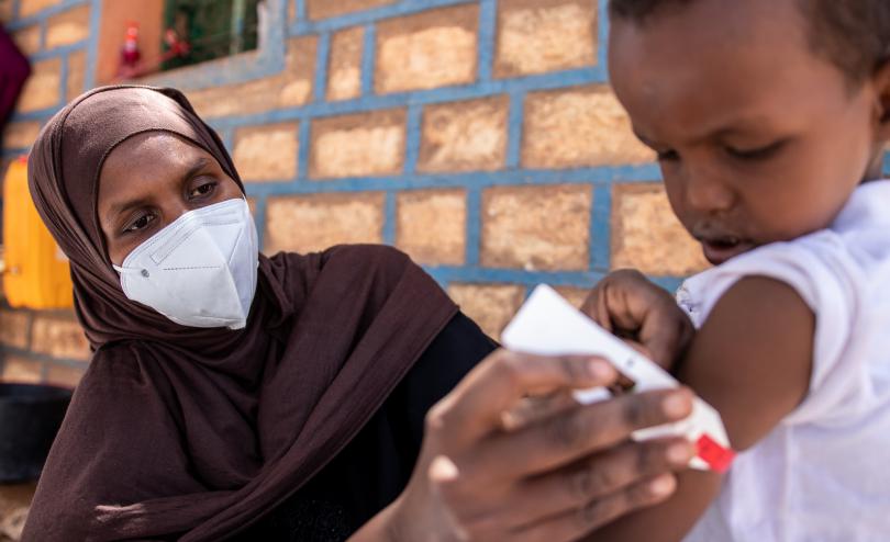 Lucky (29), who part of Save the Children's mother-led malnutrition screening programme in Somalia, screens her son Munsin (3)