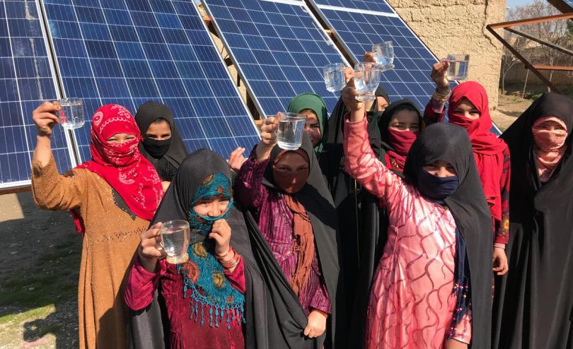 Group of girls holding up clean drinking water provided by solar powered wells, Faryab Province Afghanistan