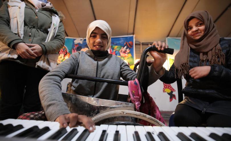 Elaf*, 17, plays the keyboard while her sister Malak*, 12, watches, North East Syria