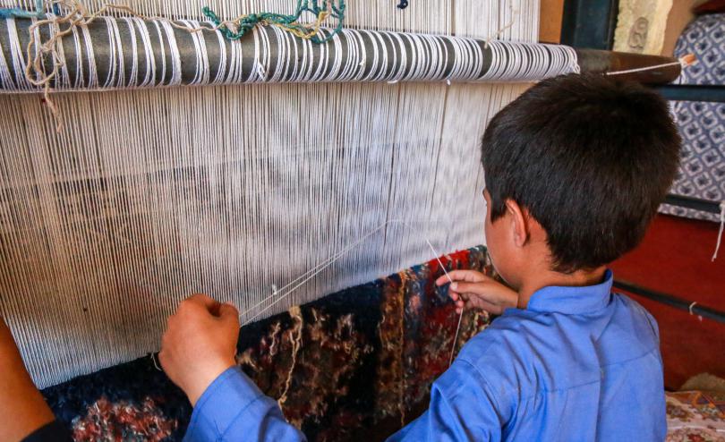 Samar*, 11, and his brother, Zalmay* (15) weave carpets to help support their family in Afghanistan