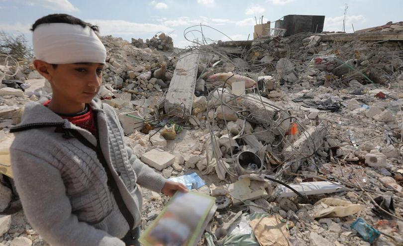 Nawras,13, holds a book he found in the rubble of his home