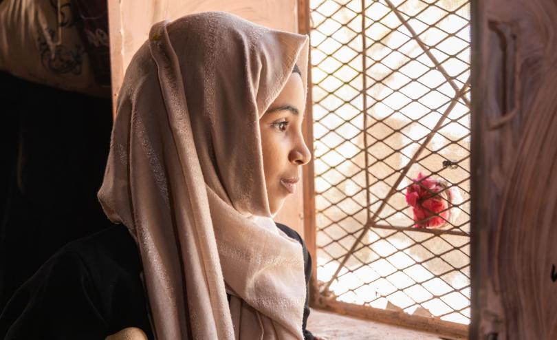 A 13-year-old girl looks out the window at her home in Yemen
