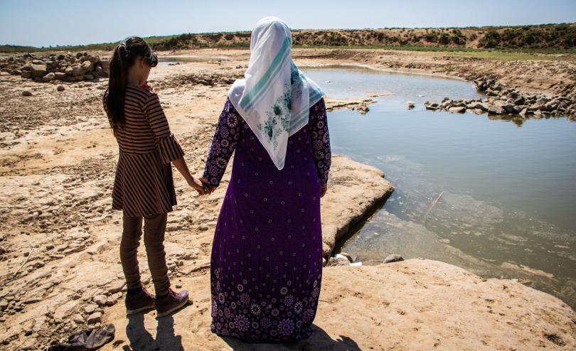 Bailasan*, 13, and her mother Maryam*, 50, look out onto the river after drought has caused a water crisis in North East Syria