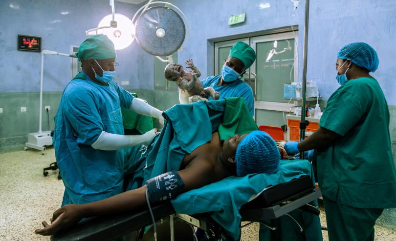 a woman has just given birth by caesarean section, surrounded by medical staff
