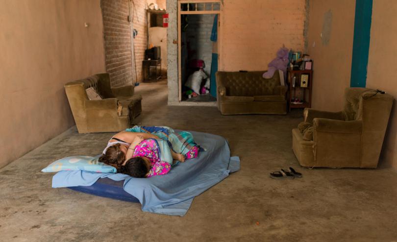 Laura and her mother sleeping in a mattres on the floor.