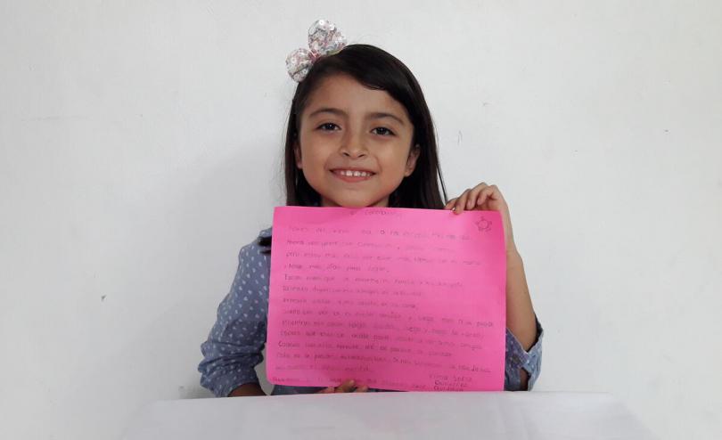 Vilma, 10, holds up her poem about coronavirus, Mexico